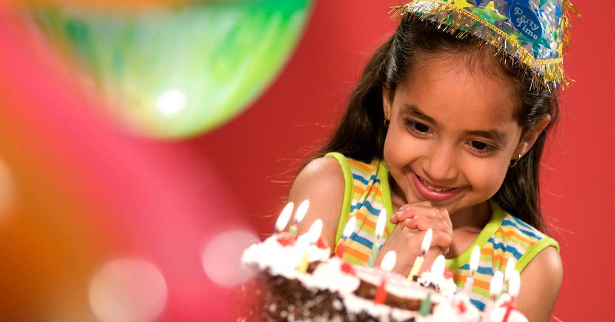Kid looking at the cake at a birthday party